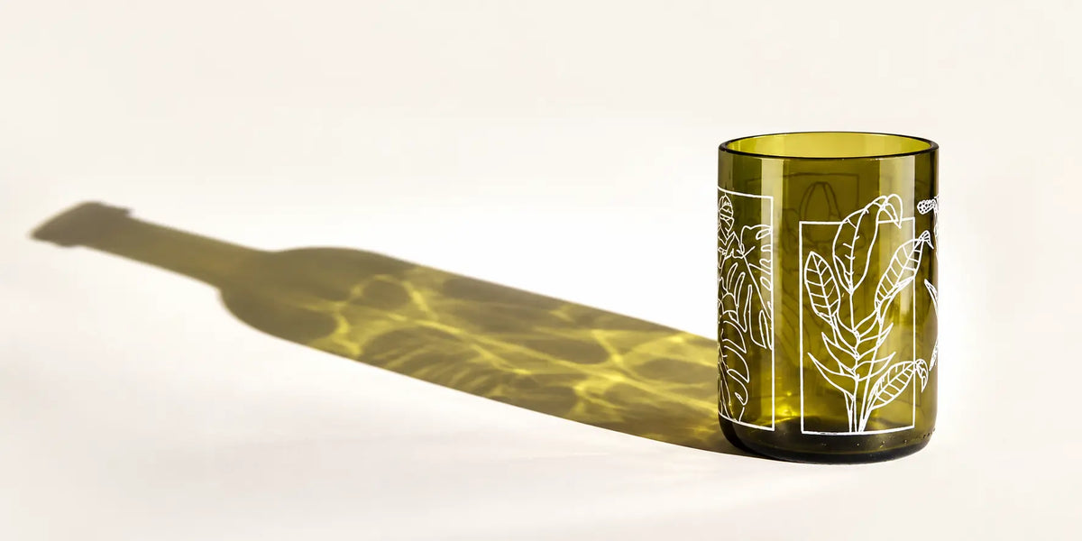 Vaso de cristal verde con ilustración blanca de hojas, hecho a partir de una botella